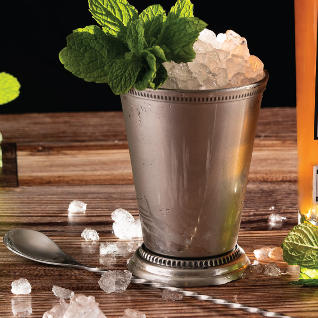 Jenny, She’s a Peach cocktail served in a julep cup, garnished with fresh mint and crushed ice.