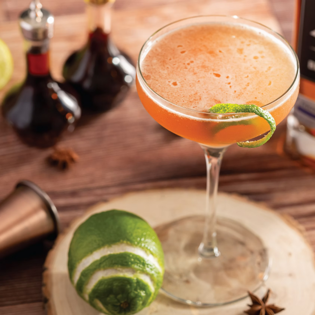 Semper Paratus bourbon cocktail with lime twist garnish in coupe glass.