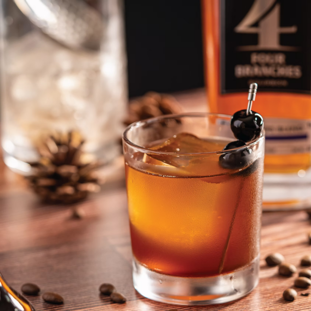 The Archibald Henderson bourbon cocktail with espresso syrup, cocoa bitters, and bourbon-soaked cherries, served in a rocks glass.