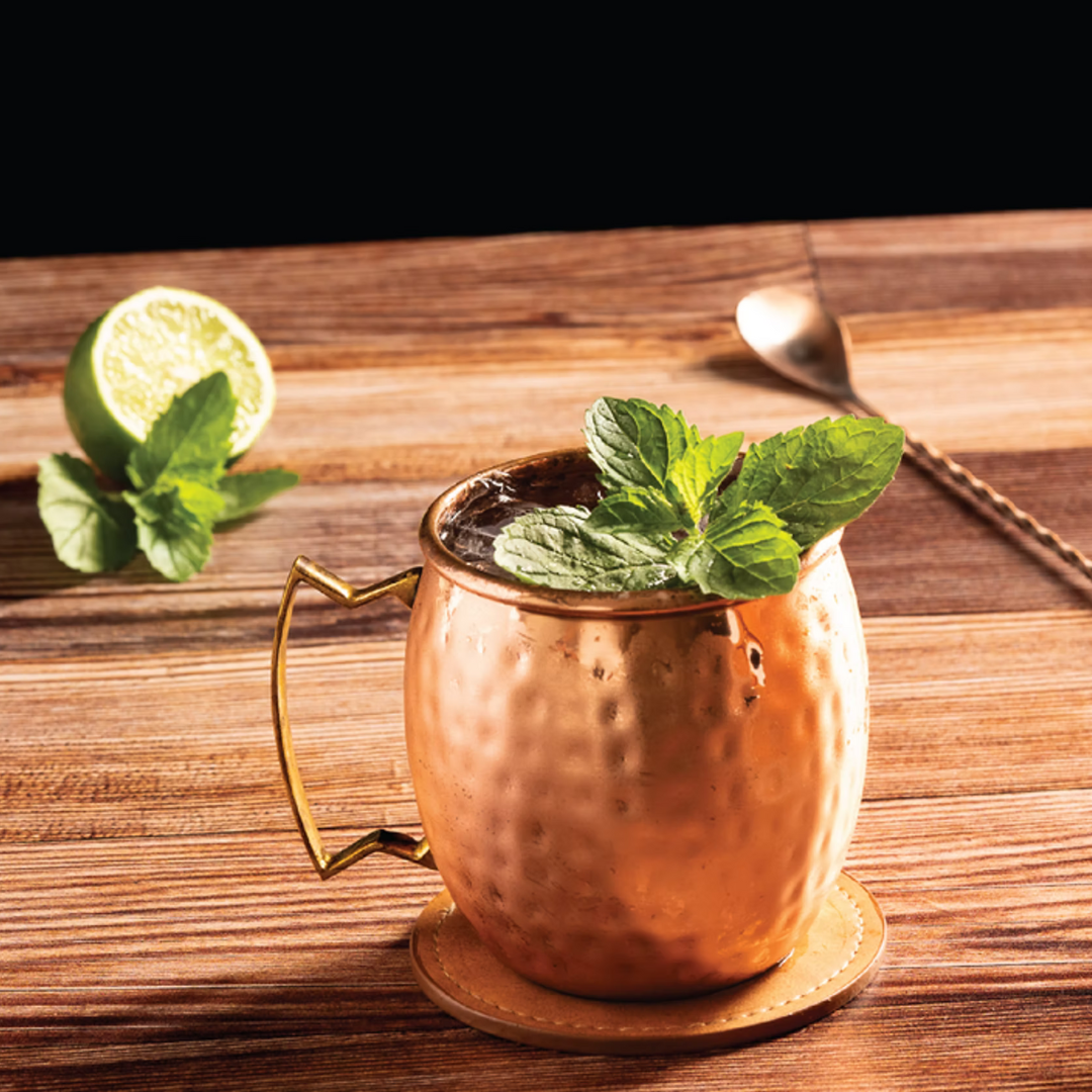 The Breacher bourbon mule cocktail in a copper mug with lime and mint garnish.
