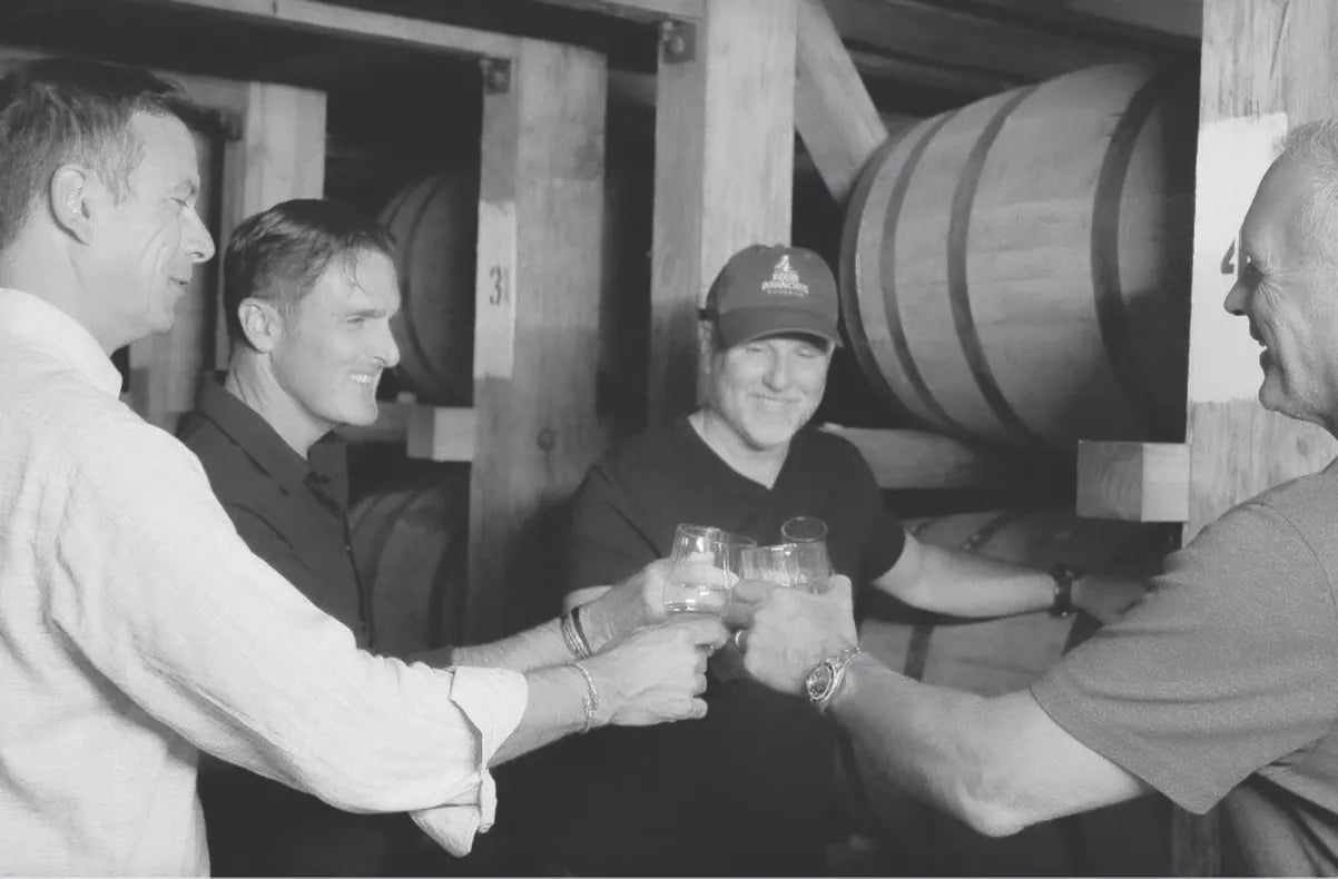The four Four Branches founders raising a glass in the rickhouse